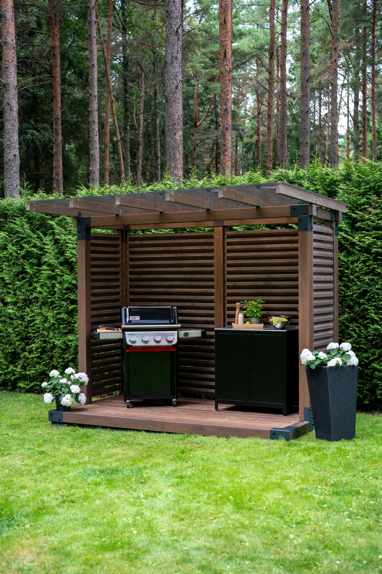 Fjordly Compact urządzony jako kuchnia zewnętrzna z grillem i szafką na akcesoria.